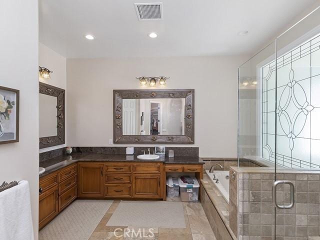 full bathroom featuring visible vents, a healthy amount of sunlight, vanity, and a garden tub