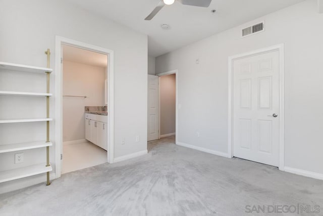 unfurnished bedroom featuring ceiling fan, light carpet, and connected bathroom