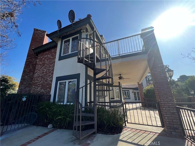 6966 Ranch View Rd, Riverside, CA 92506 - view of property exterior featuring a ceiling fan, a chimney, a balcony, brick siding, and a gate