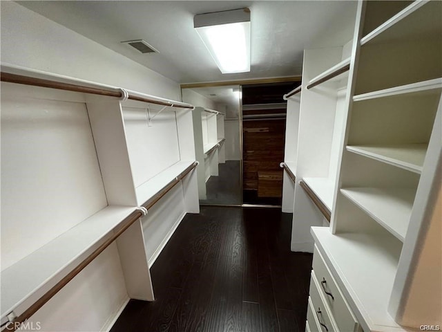 walk in closet with dark hardwood / wood-style flooring