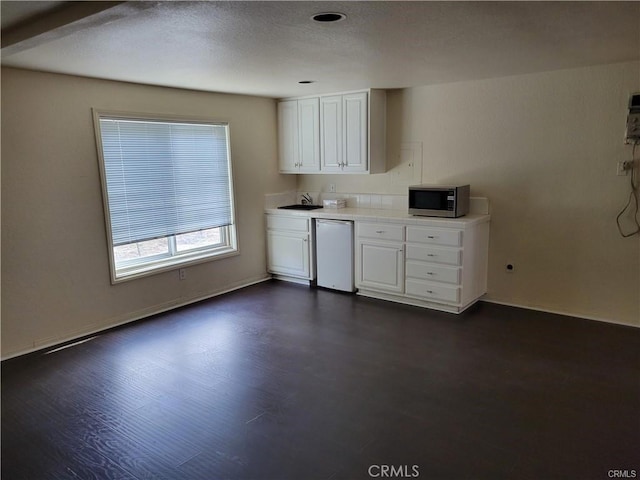 6966 Ranch View Rd, Riverside, CA 92506 - kitchen with stainless steel microwave, fridge, white cabinets, light countertops, and dark wood-style floors