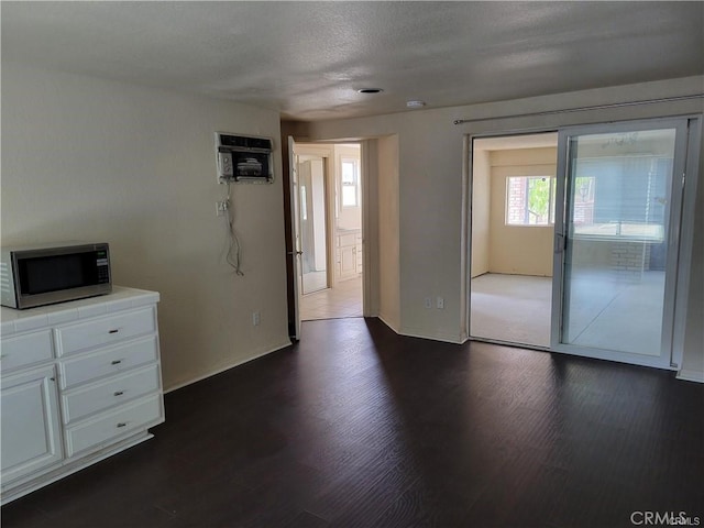 6966 Ranch View Rd, Riverside, CA 92506 - unfurnished living room with dark wood-style floors, an AC wall unit, and a textured ceiling