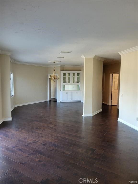 empty room with ornamental molding, dark hardwood / wood-style flooring, and a notable chandelier