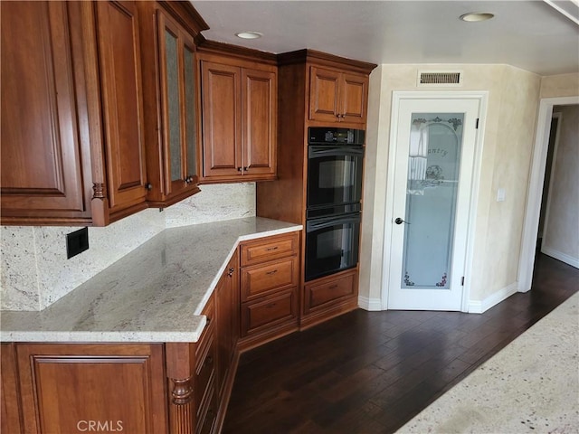 6966 Ranch View Rd, Riverside, CA 92506 - kitchen with brown cabinetry, light stone counters, decorative backsplash, dark wood-type flooring, and glass insert cabinets