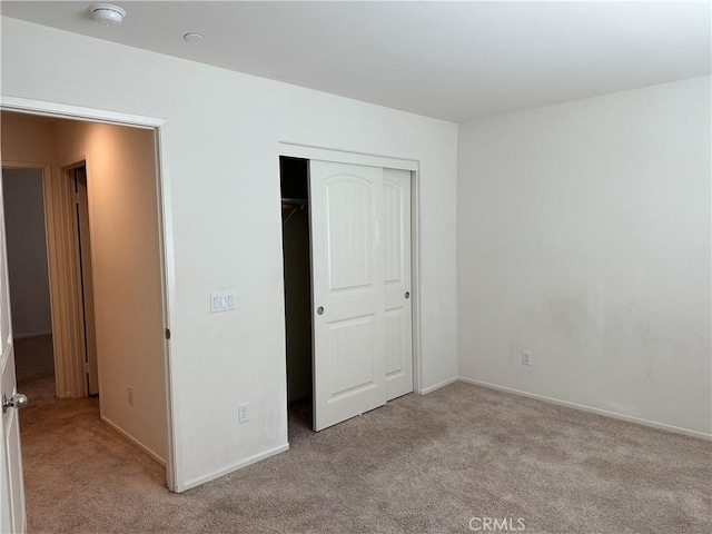 unfurnished bedroom with light carpet and a closet