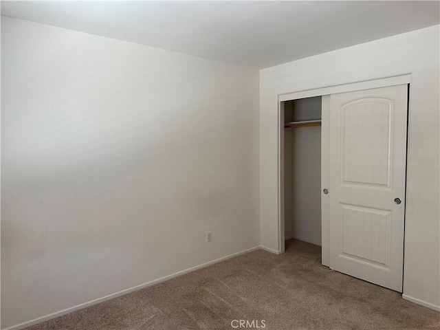 unfurnished bedroom with light carpet and a closet