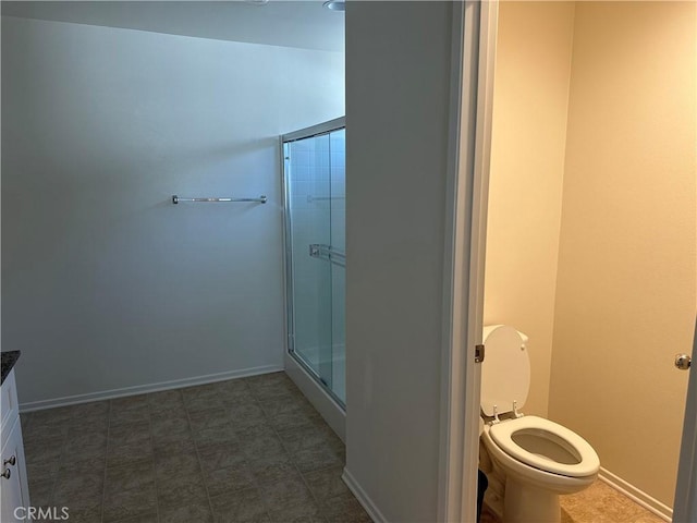 bathroom featuring a shower with shower door and toilet