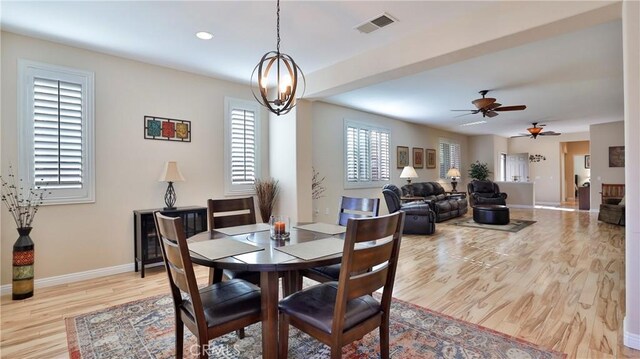 dining space featuring ceiling fan with notable chandelier and light hardwood / wood-style flooring