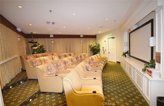 carpeted home theater room featuring crown molding