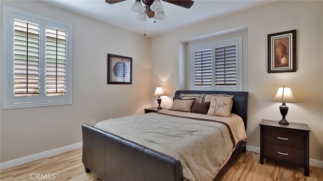 bedroom with ceiling fan, multiple windows, and light hardwood / wood-style flooring