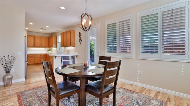 dining area with sink, an inviting chandelier, and light hardwood / wood-style floors