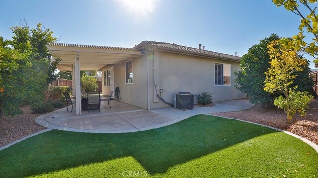 back of property with a pergola, a patio area, central AC, and a yard