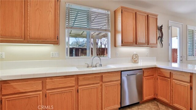 kitchen featuring sink, stainless steel dishwasher, and tile countertops