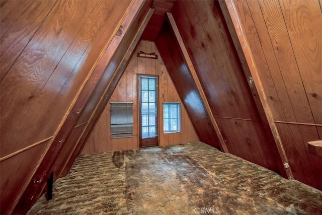 bonus room with wood walls and vaulted ceiling