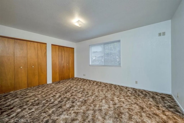 unfurnished bedroom with multiple closets and carpet flooring