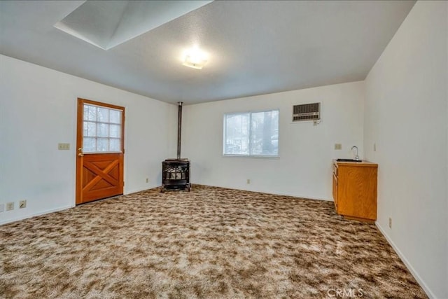 unfurnished living room featuring a wood stove, carpet flooring, and a healthy amount of sunlight