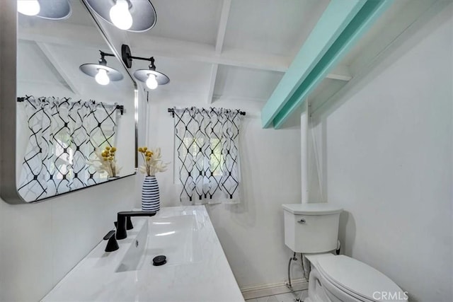 bathroom with toilet, beam ceiling, and sink