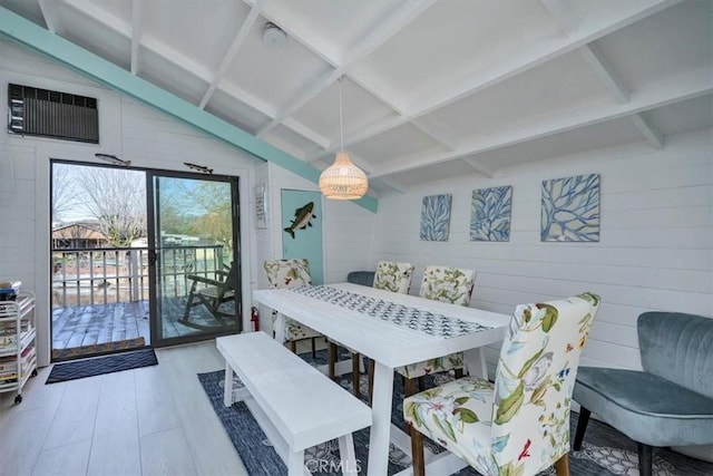 dining area featuring beam ceiling, a wall unit AC, hardwood / wood-style floors, and wood walls