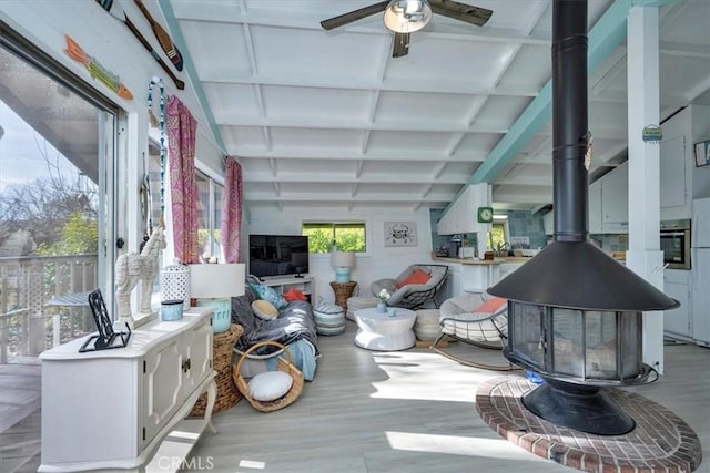 living room with ceiling fan, a wood stove, beamed ceiling, and coffered ceiling