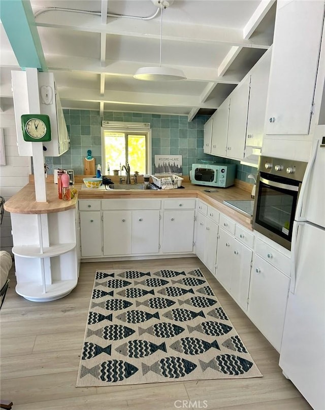 kitchen featuring white fridge, white cabinetry, stainless steel oven, and sink