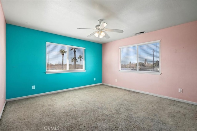 spare room with carpet floors, a wealth of natural light, visible vents, and baseboards