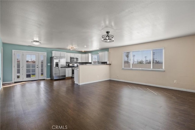 unfurnished living room featuring baseboards, dark wood-style flooring, and a healthy amount of sunlight