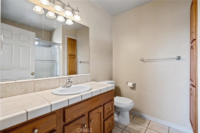 bathroom with tile patterned flooring, toilet, a shower with shower door, vanity, and baseboards