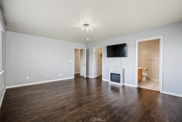 unfurnished living room with a fireplace, baseboards, and wood finished floors