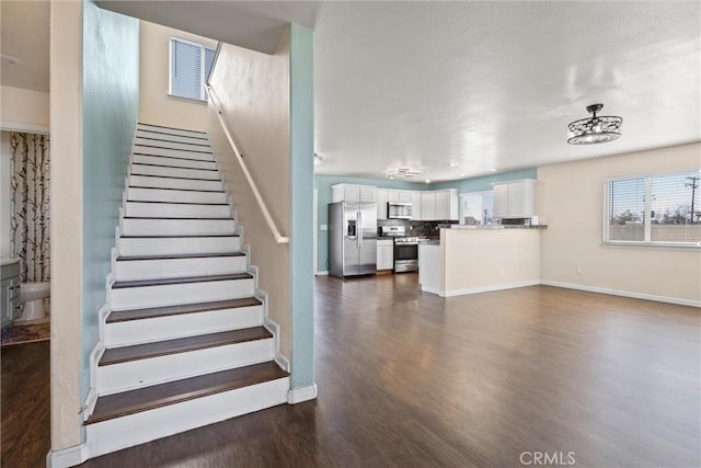 staircase featuring visible vents, baseboards, and wood finished floors