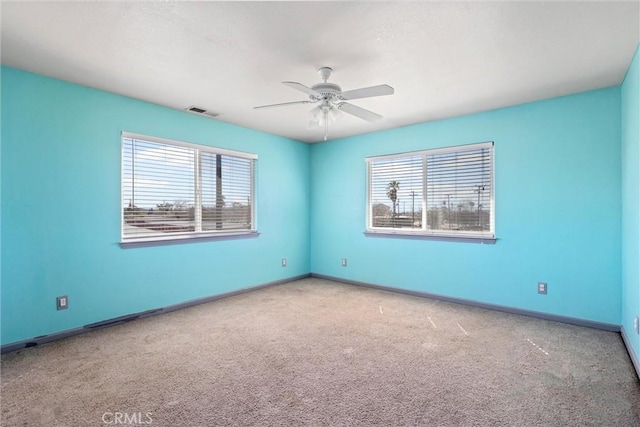 carpeted spare room featuring ceiling fan, visible vents, and baseboards