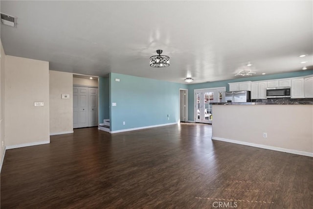 unfurnished living room with baseboards, visible vents, and dark wood finished floors