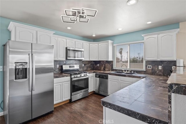 kitchen with dark wood-style floors, backsplash, appliances with stainless steel finishes, white cabinets, and a sink