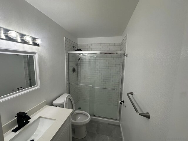 bathroom featuring tile patterned flooring, vanity, toilet, and a shower with shower door