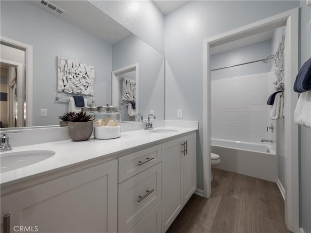 full bathroom featuring washtub / shower combination, wood-type flooring, toilet, and vanity