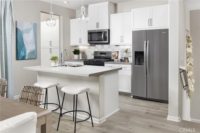 kitchen with pendant lighting, white cabinetry, stainless steel appliances, decorative backsplash, and sink