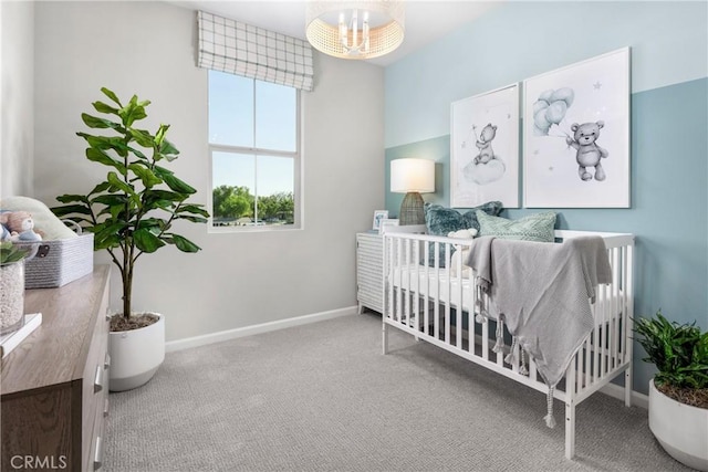 bedroom featuring carpet floors, a nursery area, and an inviting chandelier