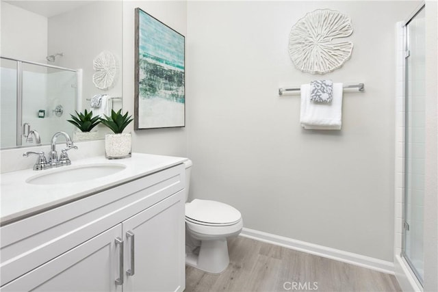 bathroom featuring toilet, wood-type flooring, an enclosed shower, and vanity