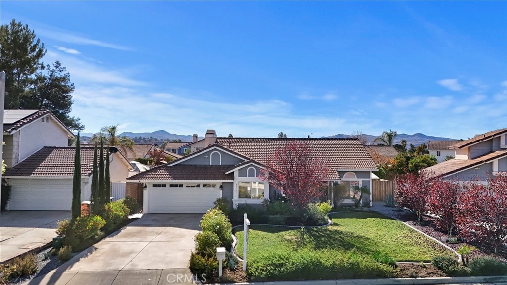 ranch-style home with a front lawn, a mountain view, and a garage