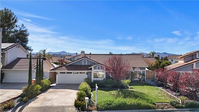 ranch-style home with a front lawn, a mountain view, and a garage