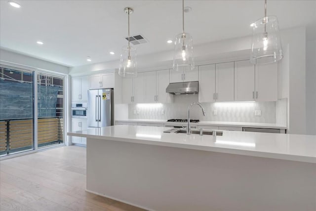 kitchen with hanging light fixtures, white cabinets, sink, and high end refrigerator