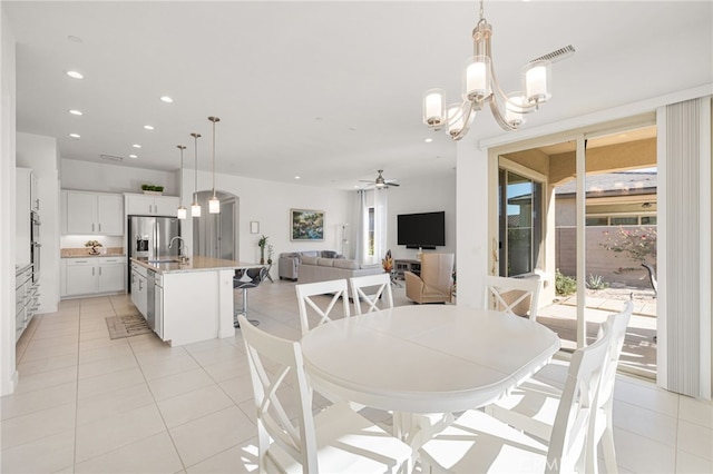 tiled dining area with ceiling fan with notable chandelier