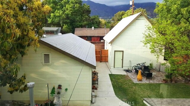 view of property exterior featuring a lawn, a patio area, and a mountain view