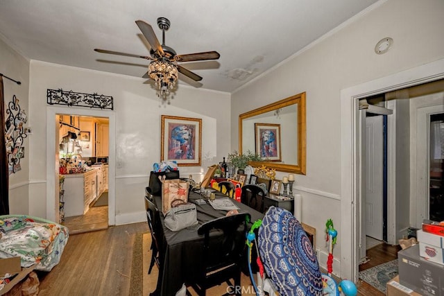 dining room featuring wood finished floors, a ceiling fan, and crown molding