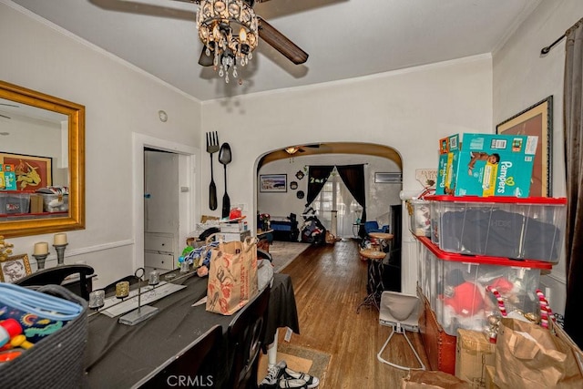 dining room featuring arched walkways, ornamental molding, wood finished floors, and a ceiling fan