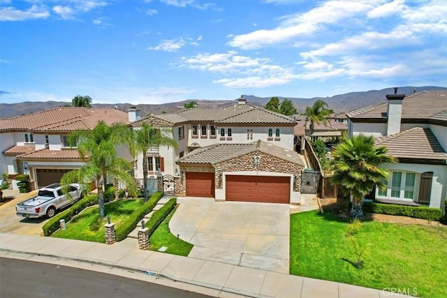 mediterranean / spanish home featuring a front lawn, a mountain view, and a garage