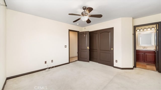 unfurnished bedroom with ceiling fan, light colored carpet, ensuite bathroom, sink, and a closet