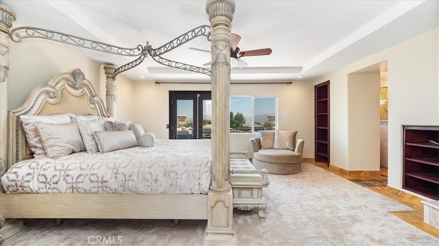 bedroom with ceiling fan, access to outside, and a tray ceiling