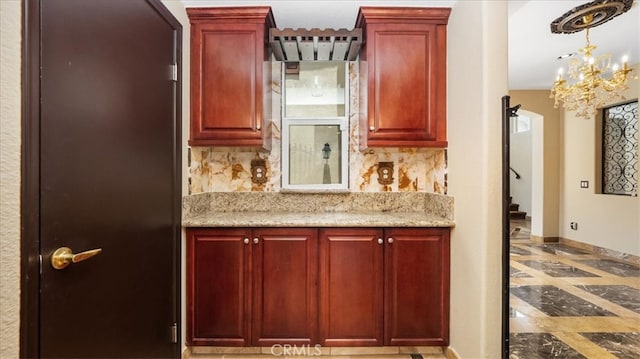 kitchen with light stone countertops, decorative backsplash, and a notable chandelier