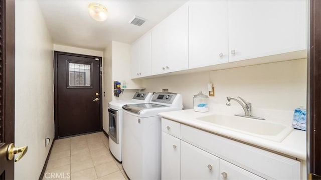 washroom featuring light tile patterned floors, washing machine and dryer, sink, and cabinets