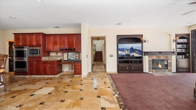 kitchen featuring appliances with stainless steel finishes, decorative backsplash, and a fireplace